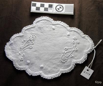 Overall oval shaped white doily embellished with embroidered flowers and crocheted edging