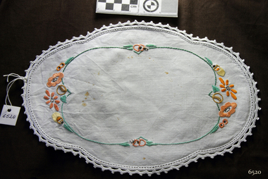 Overall oval, white doily with orange, yellow and green floral embroidery and crocheted gentle scalloped edges