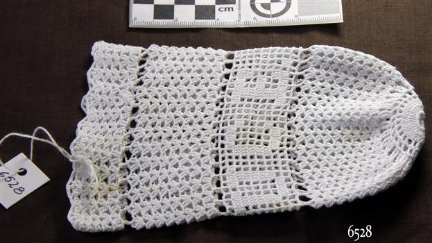 White tubular crocheted cover is slightly flared outward at the base and drawn together at the top.
