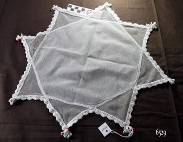 Eight-point shaped net cover with crocheted edges, and white, red and green beads at the points 