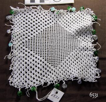 White crocheted square with central diamond pattern and alternate blue, green and clear beads on the border