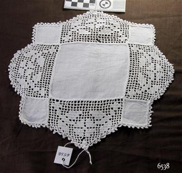 White crocheted pieces inserted between a large cotton square and four small cotton squares, with a crocheted border around it.