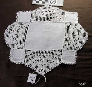 White crocheted pieces inserted between a large cotton square and four small cotton squares, with a crocheted border around it.