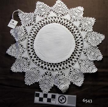 White cotton fabric doily, round centre with crocheted border with points like a sun