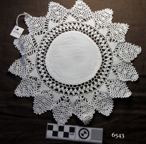 White cotton fabric doily, round centre with crocheted border with points like a sun