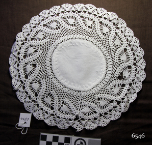 Round white doily with embroidered fabric centre and wide crocheted border