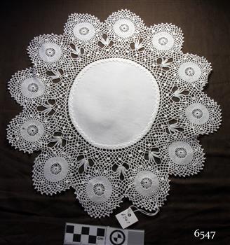 White round fabric embroidered centre with a deep border of circular crocheted sections