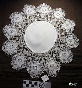 White round fabric embroidered centre with a deep border of circular crocheted sections