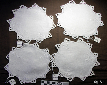 White fabric oval shaped embroidered doilies, set of four, with scalloped edges and crocheted trim