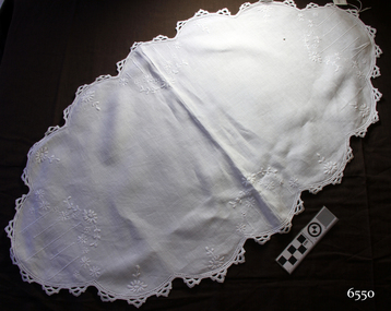 White cloth, embroidered tray cover, oval shaped with scalloped edges and crocheted border