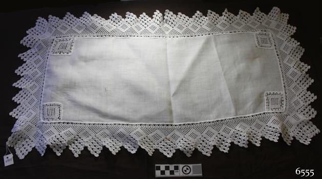 White rectangular table runner with square crocheted inserts in corners and crocheted edging