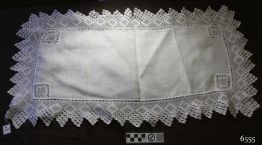 White rectangular table runner with square crocheted inserts in corners and crocheted edging