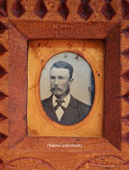 Portrait of a male in shirt, jacket and tie. Man has a beard below the chin and a long moustache