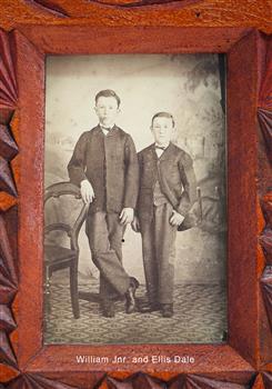 Two standing male children wearing shirts, ties, jackets and trousers