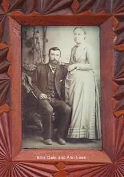 Studio photograph, seated male with beard, moustache and suit. Standing female with pale coloured long dress