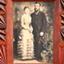 Standing couple; female in long light dress with flounces, male in suit with waistcoat and tie.