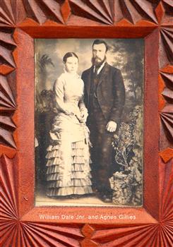 Standing couple; female in long light dress with flounces, male in suit with waistcoat and tie.