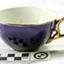 Royal blue teacup with gold trim on rim and base and gold handle. Inside is white.
