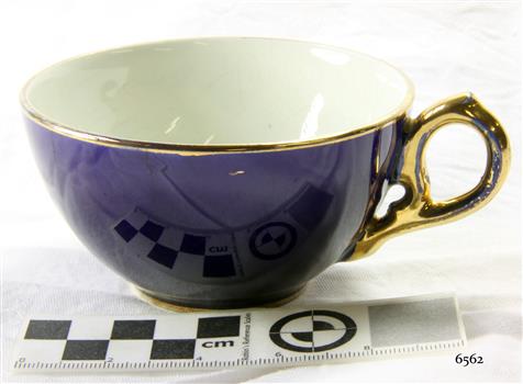 Royal blue teacup with gold trim on rim and base and gold handle. Inside is white.