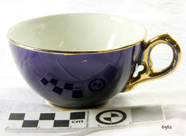 Royal blue teacup with gold trim on rim and base and gold handle. Inside is white.