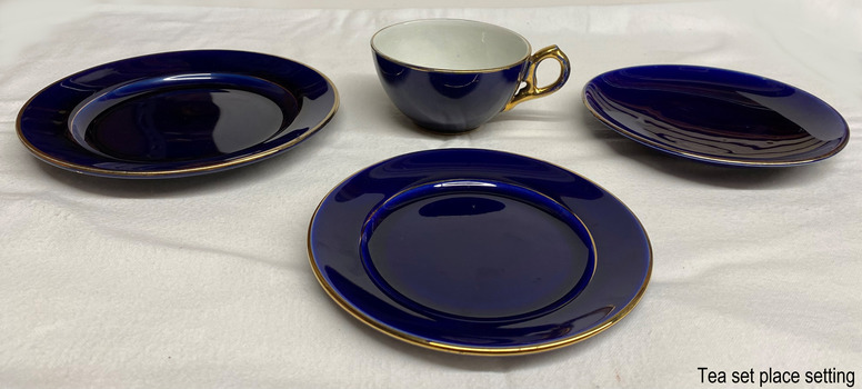 Four pieces in blue and gold ceramic; cup, saucer, small plate, large plate
