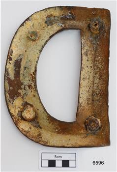 Back of letter is hollow and has accumulated sediment and corrosion. Round fixing points are mounted in the metal.