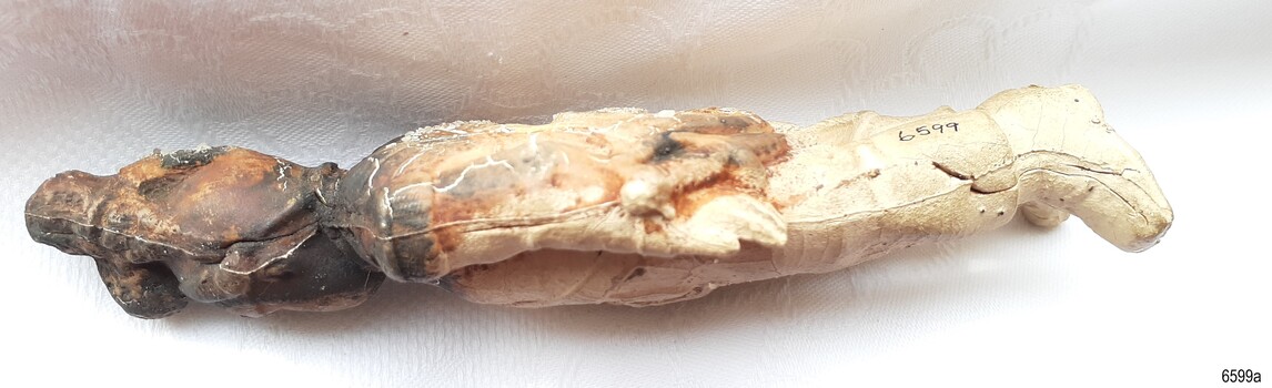 Seam runs along figure from helmet to toe. Surface has fine cracks.
