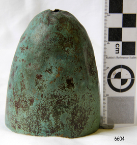 Green verdigris on dome-shaped metal object with a hole in the top 