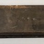 Rectangular black box with scratches and blobs of paint, and metal hook and eye catch