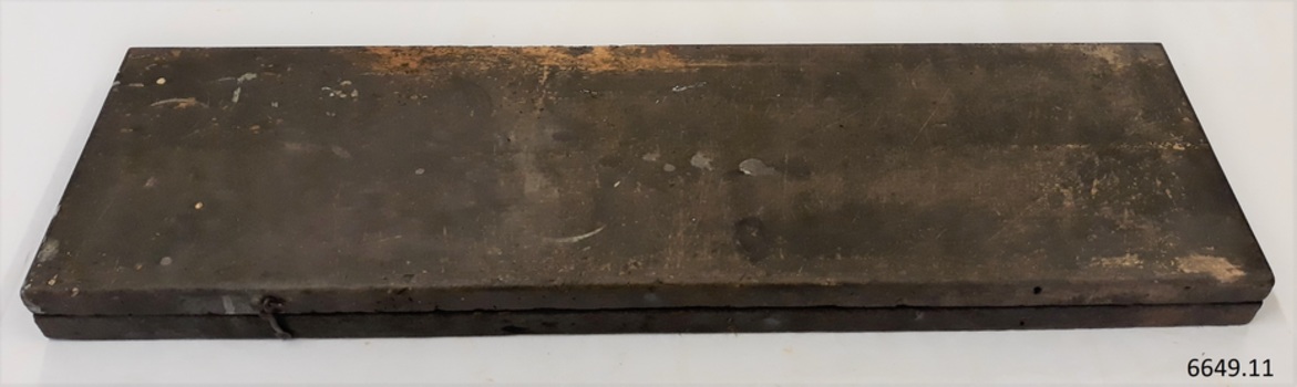 Rectangular black box with scratches and blobs of paint, and metal hook and eye catch