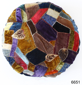 Multi coloured patchwork cushion, round, with cross stitching joins