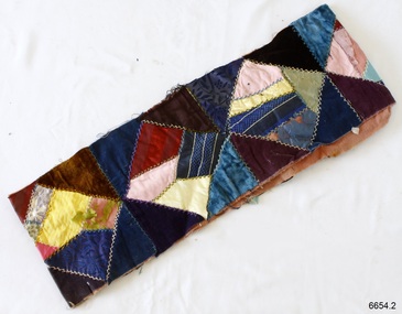 Rectangle of various colours and designs of fabric sewn together, decorated with blanket stitch