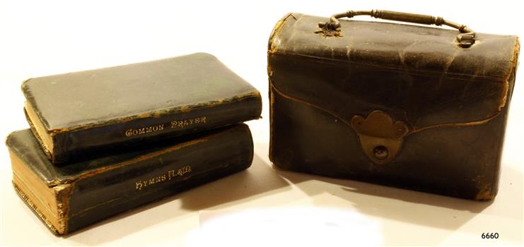 Leather covered carrying case beside two leather covered books