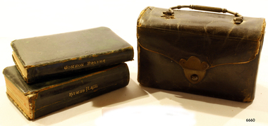 Leather covered carrying case beside two leather covered books