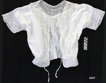 White cotton camisole with short sleeves and buttons on the front, lace trim collar and on sleeves, drawstring waist