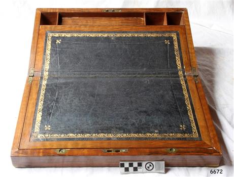 Leather writing surface has gold painted decorative border