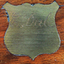 Shield shaped brass plaque has an inscription 