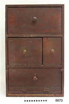 Wooden cupboard with four sections, each wit a round wooden knob