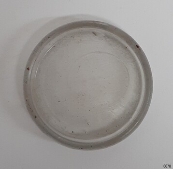 Black tinged clear glass disc with ridge around the outside and an air bubble ring