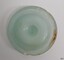 Opaque green disc with outer ridge. Chips and discolouration on the surface