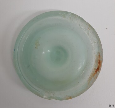 Opaque green disc with outer ridge. Chips and discolouration on the surface