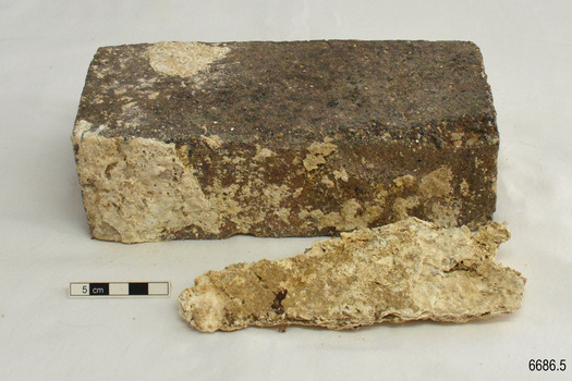 A piece of the concretion has broken off. The sides of the brick are uneven