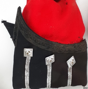 Black cuff on red tunic sleeve has  upward curve on the outer top edge, divided at the seam