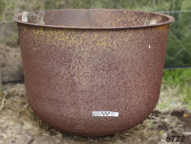 Round metal pot with rounded base and flat extended lip. Metal is rough, corroded and chipped, and a crack extends from the lip down.
