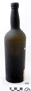 Light shining through bottle shows its dark green colour. There is white sediment on the outside down one side.