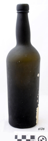Light shining through bottle shows its dark green colour. There is white sediment on the outside down one side.