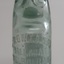 upright glass bottle with marble in neck and moulded inscriptions