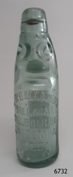 upright glass bottle with marble in neck and moulded inscriptions