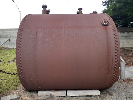 Large cylindrical boiler with pipe fittings on top