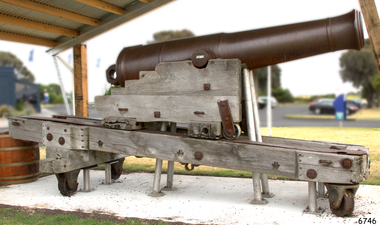 Cannon mounted on wooden carriage, undercover.